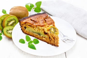 Pie with kiwi in plate on wooden light board