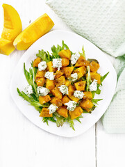 Salad of pumpkin and cheese in plate on light board top
