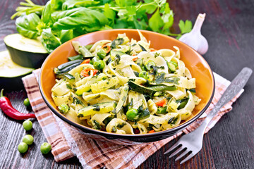 Tagliatelle with green vegetables on dark wooden board