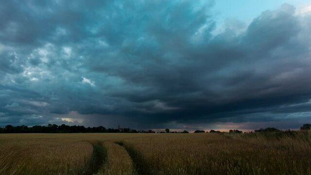 Dark rain clouds moving over the open farm field in Zlotoryja, Poland - time lapse
