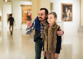 happy english father and daughter looking at paintings in halls of museum