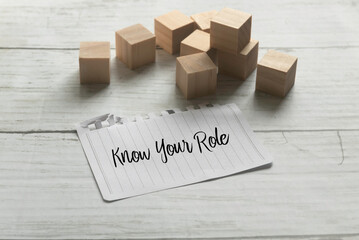 Selective focus of wooden cubes and paper written with Know Your Role on white wooden background.