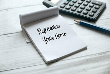 Selective focus of pencil,calculator and notebook written with Refinance Your Home on white wooden background.