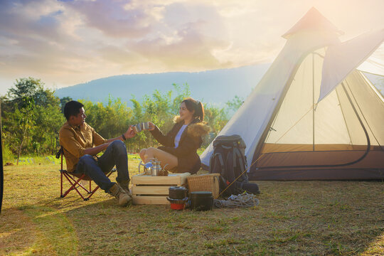 Young couples have good time morning on camping trip with sunrise background. Couples enjoy camping 