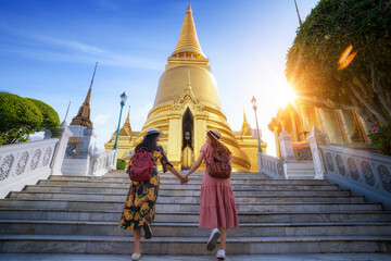 Two asian girlfriends traveling and check location by a map in Grand Palace and Wat phra kaew...