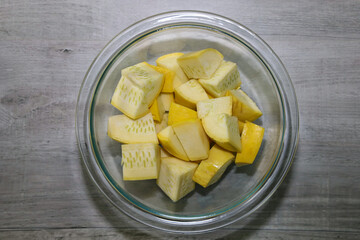 Yellow squash cut up in a glass bowl to use in albondiga soup recipe.