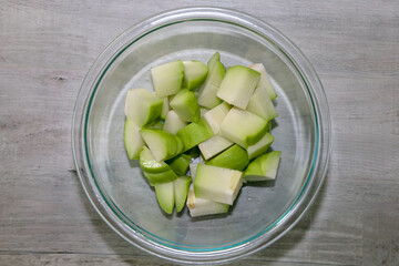 Chayote or vegetable pear cut up in a glass bowl for making albondiga soup.