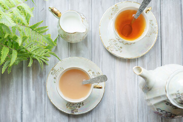 Traditional five o'clock English tea in an elegant china set. Two cups of tea and milk on a wooden vintage tray. Flat lay.