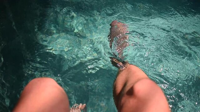 POV Sitting Poolside Dangling Legs in Water, Relaxing Vibes - High Angle