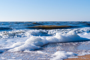 Image of sea foam on a sandy beach.