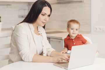 Businesswoman mother woman with small child son working online computer home office