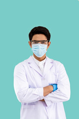 Portrait of confident male Asian researcher scientist medical doctor wearing surgical mask and protection glasses standing cross arms isolated on light green background