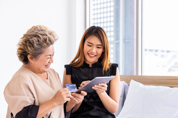 Happy senior elderly Asian woman female mother and daughter enjoy online shopping using digital tablet
