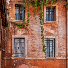 Fototapeta na wymiar grunge house orange wall and four windows in Trastevere, Rome Italy