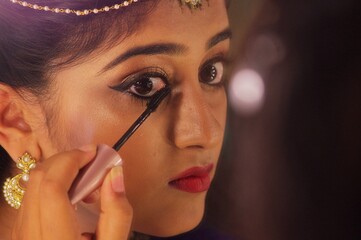 An Indian girl applying eyeliner