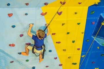 6 years old child climbing on a wall in a climbing center