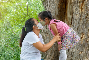 Asian woman and a little girl daughter wearing homemade face mask kissing. 
