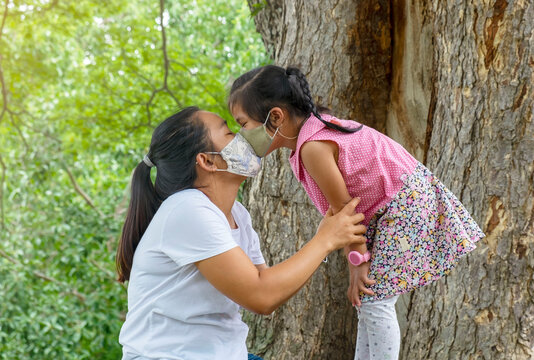 Asian Woman And A Little Girl Daughter Wearing Homemade Face Mask Kissing. 