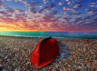 Red rescue boat on coast of Black Sea under dramatic sunset clouds