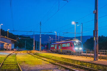 Fototapeta premium Passenger train stopping on a station of Preserje in Slovenia. during evening hours. Evening setting of an newer type of commuter train.