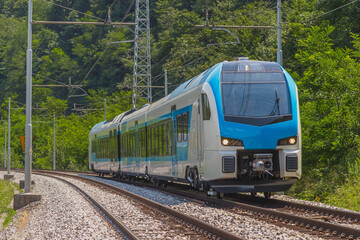 Modern and new passenger swiss made Train in white and blue color is traveling on a dual track...