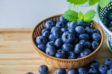 Fresh ripe blueberries in basket on wooden background.
