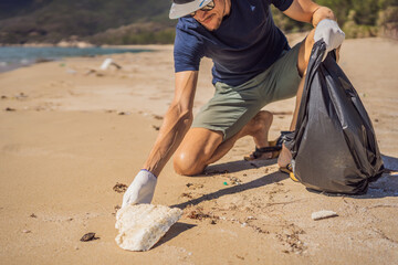 Man in gloves pick up plastic bags that pollute sea. Problem of spilled rubbish trash garbage on the beach sand caused by man-made pollution and environmental, campaign to clean volunteer in concept