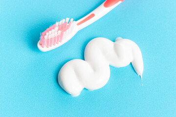 A small smear of toothpaste and toothbrush on a blue background