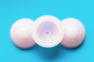 Three pink vacuum jars for anti-cellulite massage on blue background top view.