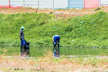 two African men cleaning up a polluted river in Cape Town, South Africa concept environmental care and awareness in Africa