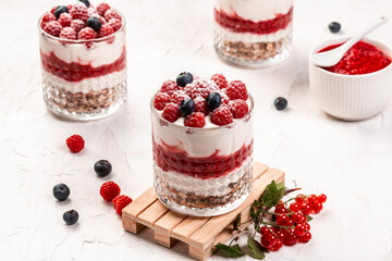 jars with tasty parfaits made of granola, berries and yogurt on white table. Healthy raspberry fruit dessert, place for text, banner