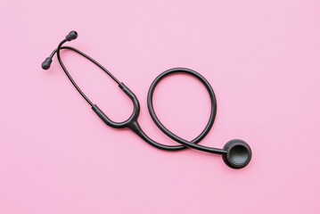 Fototapeta premium Black modern stethoscope on pastel pink background.