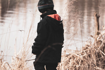 little boy walks with his family in the woods near river