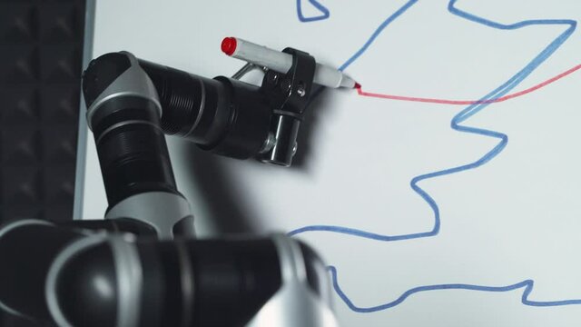 Programmed robot draws a picture, a futuristic robot hand draws a marker on a blackboard, robot learns to draw, modern technology.
