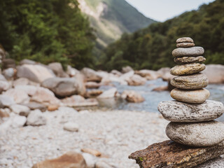 Closeup shot of a carefully built rock cairn located on the tranquil river bank of a alpine river in Switzerland.