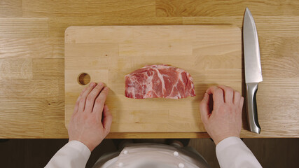 TOP VIEW: Cook ready to cut pork on a cutting board
