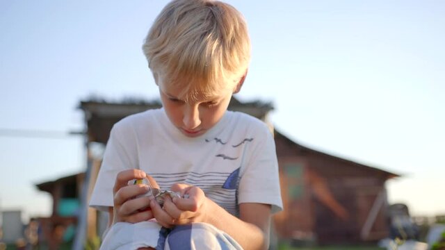 A little boy unfolds and eats a chocolate egg with toys.