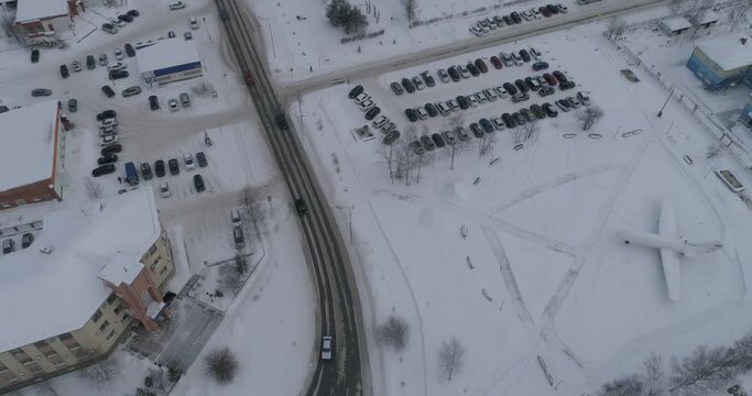 Aerial view of winter city. In the shot are residential buildings and Gazprom main office building. There is snow on the roads, Cars drive on the road. Near the expensive square and monument-aircraft.