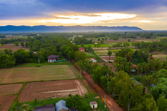 A Top Down Aerial View Of A Small Country Town With Traditional Houses In Sunset Besides Mountain In Cambodia.