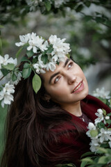 a girl in a flowery garden in a maroon coat