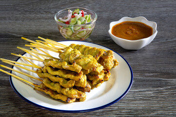 Pork satay in white dish and sauce satay put on gray wooden table
