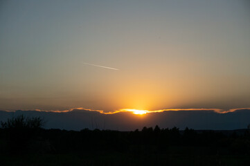 the setting sun and the streak of a passing plane