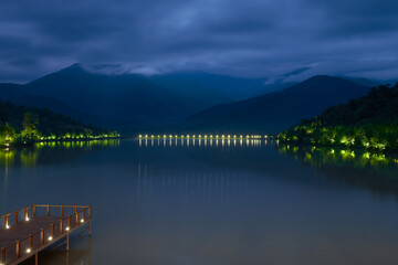 Lake in the mountains. Night landscape of the lake with lights and mountains. Selective focus