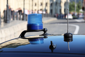 Blue flashing light and communication antennas on a government car on a city street. Concept of...