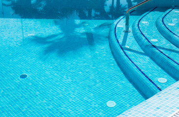 Pool stairs water blue. Step down to the pool. Railing and stairs to the pool. Selective focus