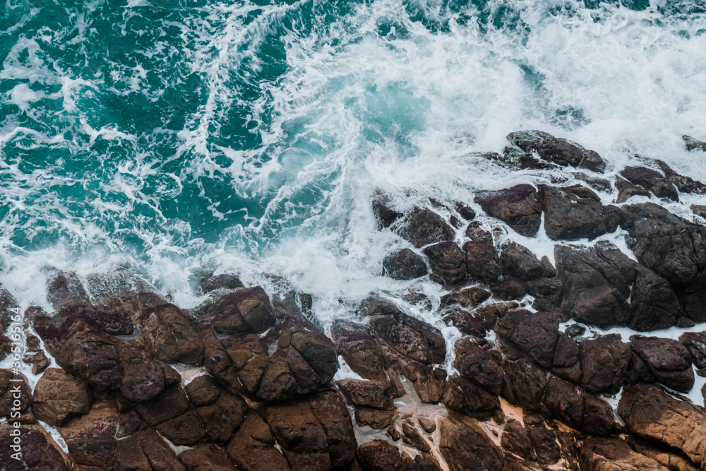 Wall mural aerial view of crashing waves on rocks.
