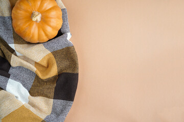 Autumn composition Flatlay. Orange pumpkin, plaid, dry autumn leaves, cones on a pastel beige background. Autumn minimalism concept, banner. Flat bed, top view.