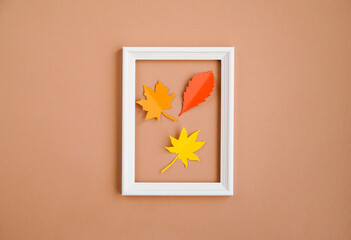Frame with decorative paper leaves on a beige background. Greeting card, autumn season, thanksgiving. Minimum concept, autumn composition.  Top view,  flat lay, copy space
