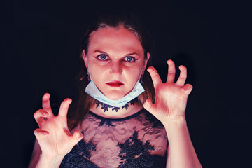 Angry look of a vamp woman with a medical mask on her face. Girl with makeup vampire for halloween...