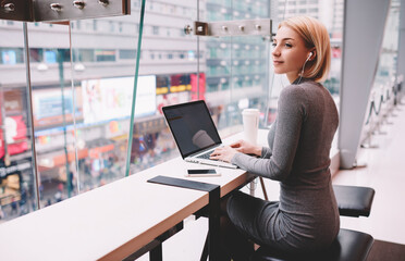 Talented female journalist typing text of article listening to radio broadcast